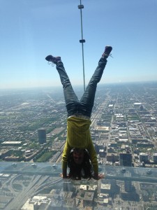 This photo is taken of a woman in SkyDeck as she faces Chicago's skyline upside down.